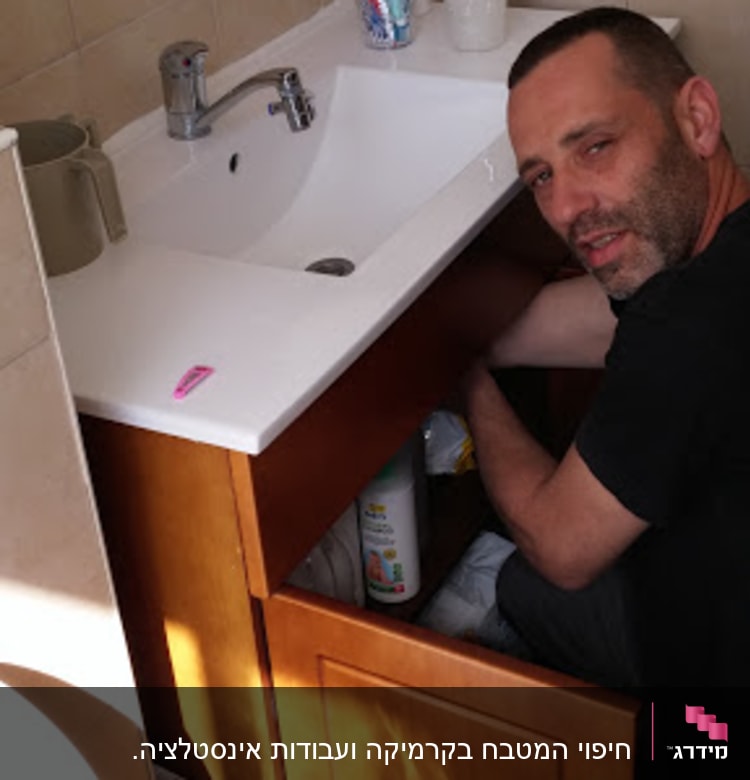 אדם מתקן ארון מתחת לכיור בחדר אמבטיה